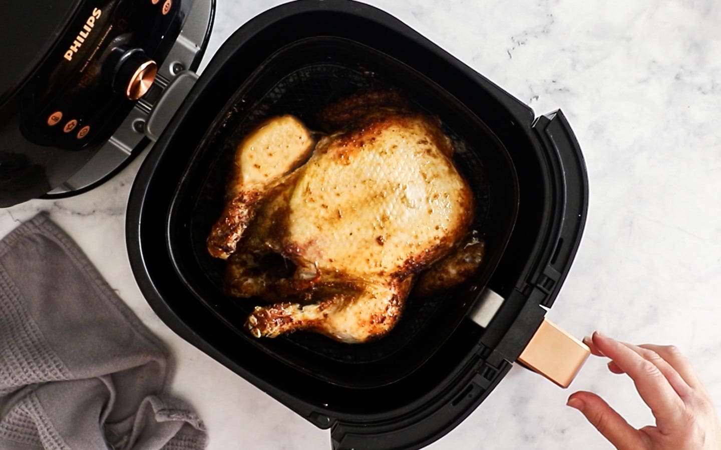 Whole chicken in the air fryer basket flipped to show the breast side.