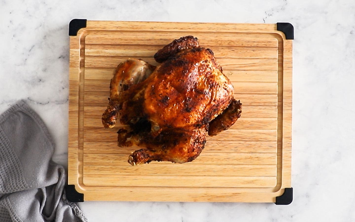 A whole air fryer chicken on a cutting board, resting.