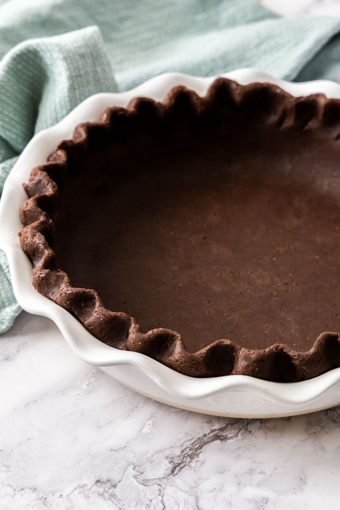 An unbaked chocolate pie crust in a white pie dish.