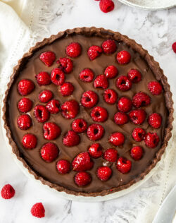 Top down view of a chocolate tart studded with raspberries.