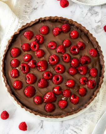 Top down view of a chocolate tart studded with raspberries.