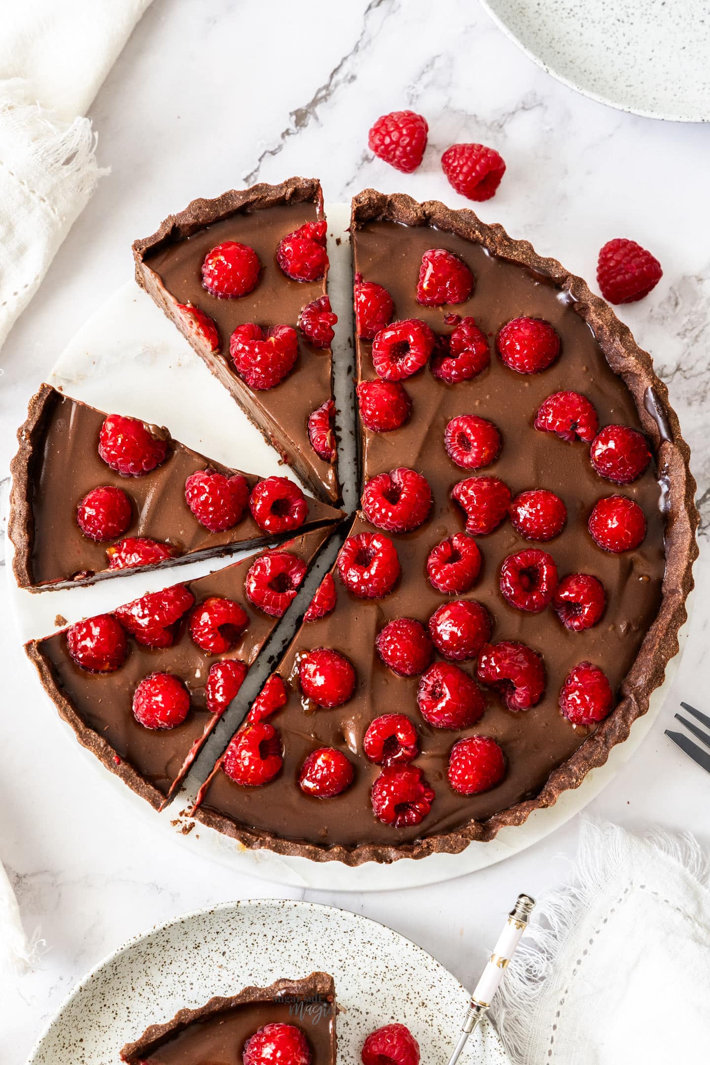 Top down view of a choc raspberry tart cut into slices.