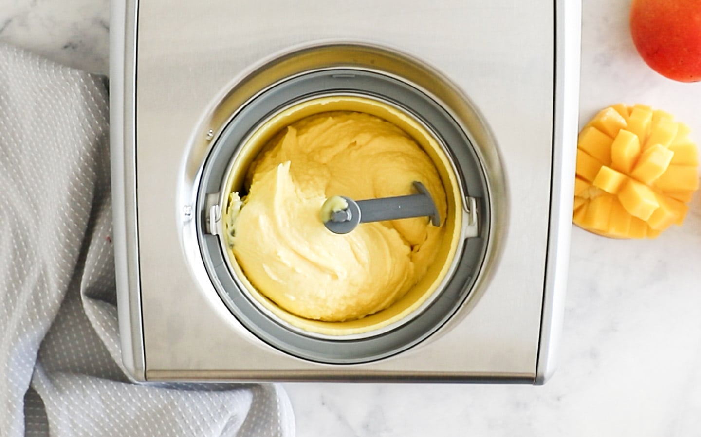 Top down view of mango gelato in an ice cream machine.