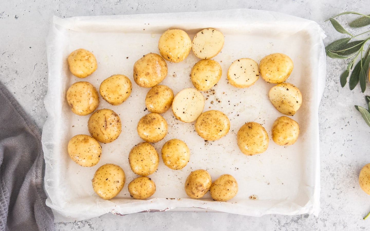 Baby potatoes seasoned with salt and pepper on a baking tray.