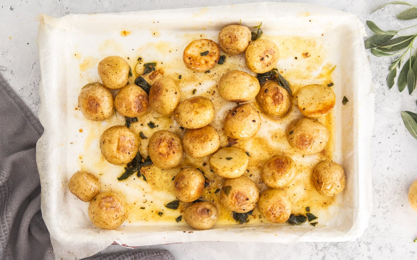 The roasted potatoes dressed with sage browned butter on a baking sheet.