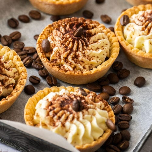 A batch of tartlets on a metal tray, surrounded by coffee beans.