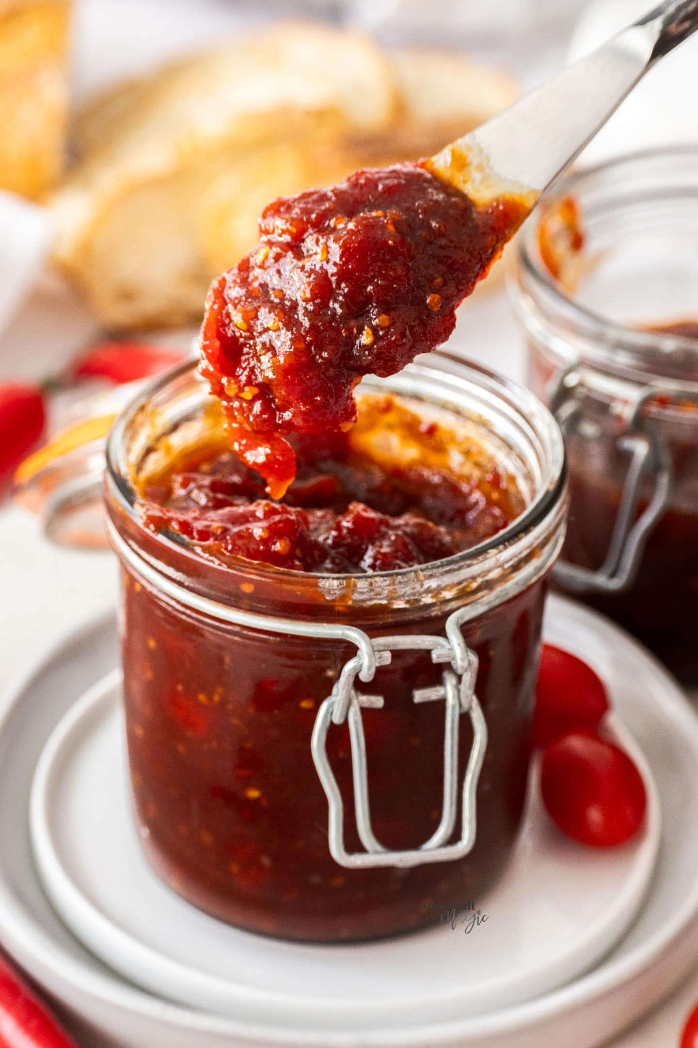 A knife scooping jam from a jar.