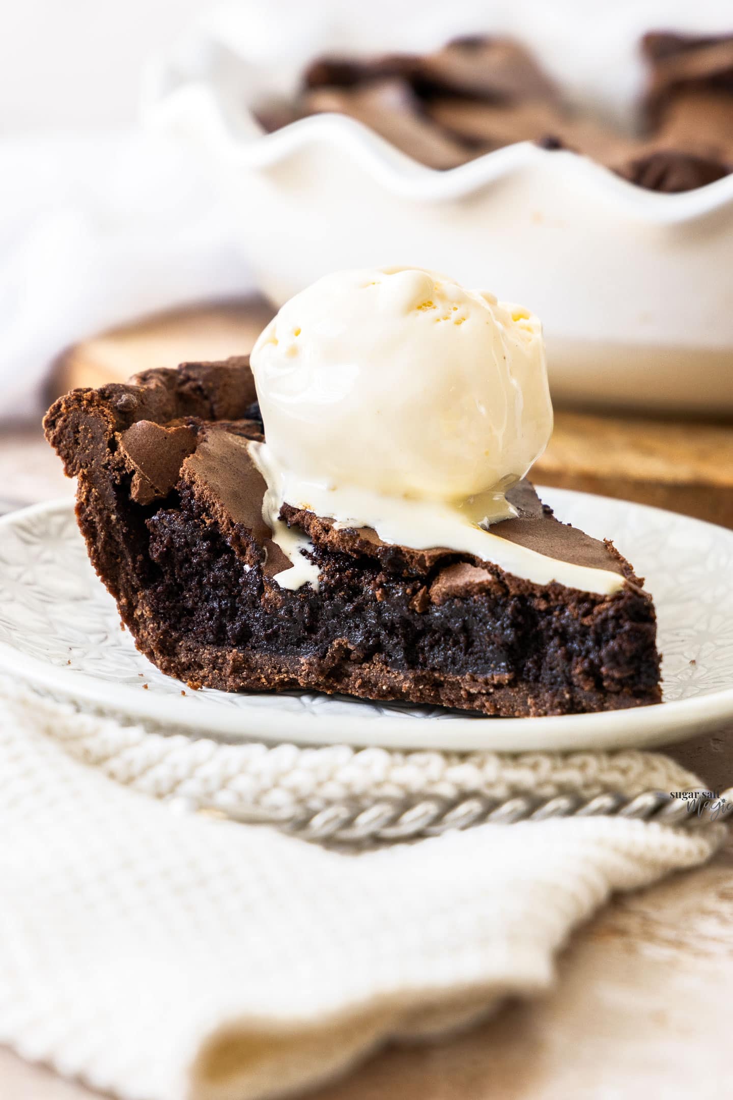 A slice of brownie pie on a dessert plate with a scoop of ice cream.