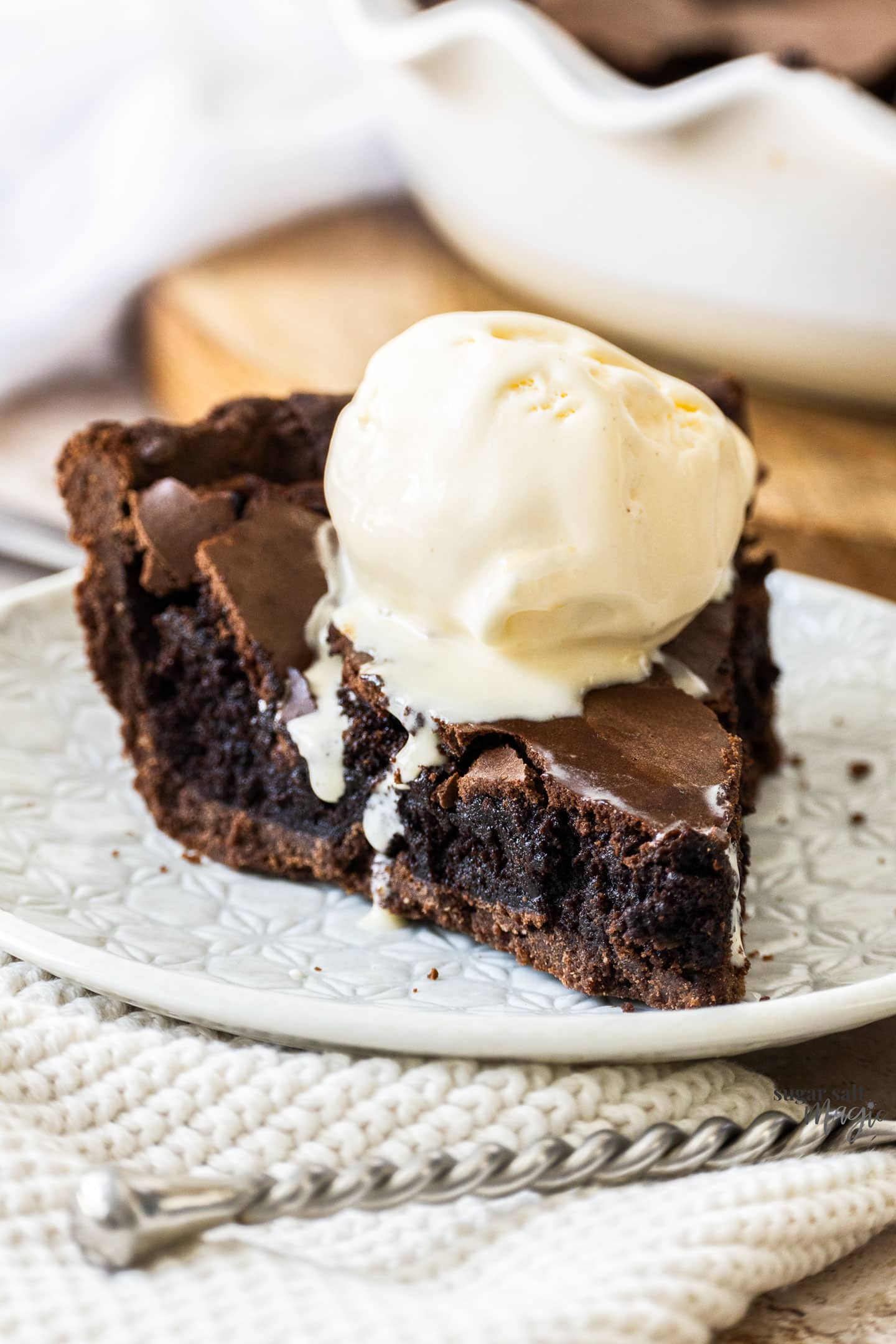 Closeup of a slice of brownie pie with ice cream on top.
