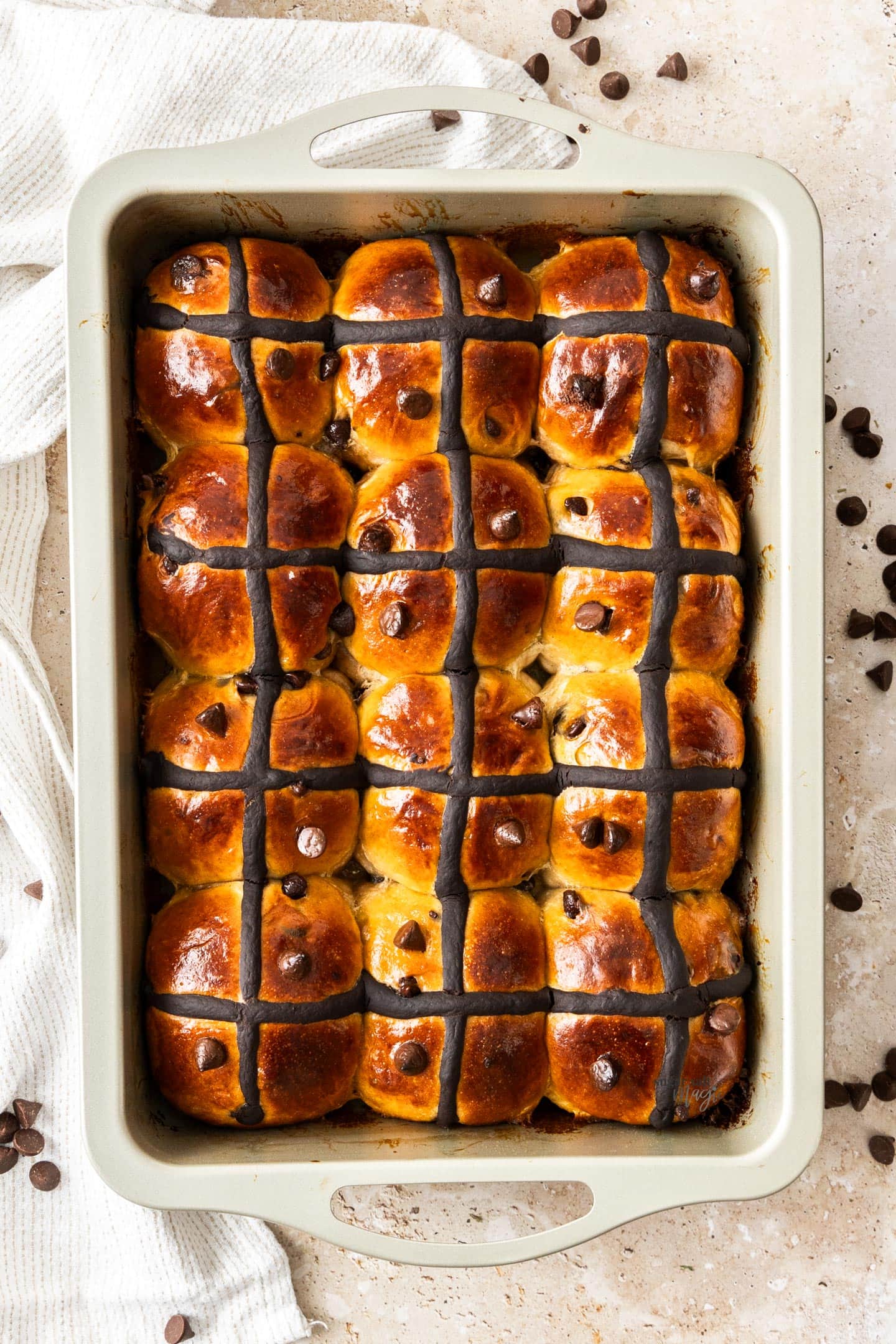 Top down view of 12 hot cross buns in a pan.