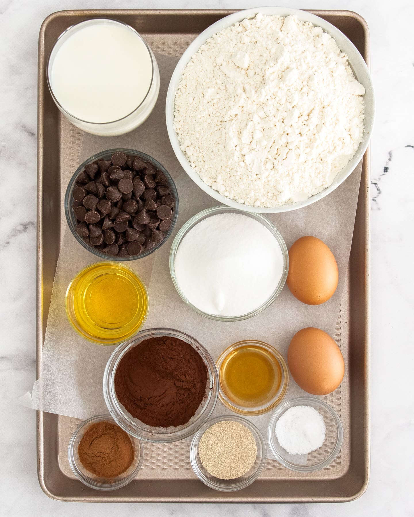 Ingredients for chocolate chip hot cross buns on a baking tray.