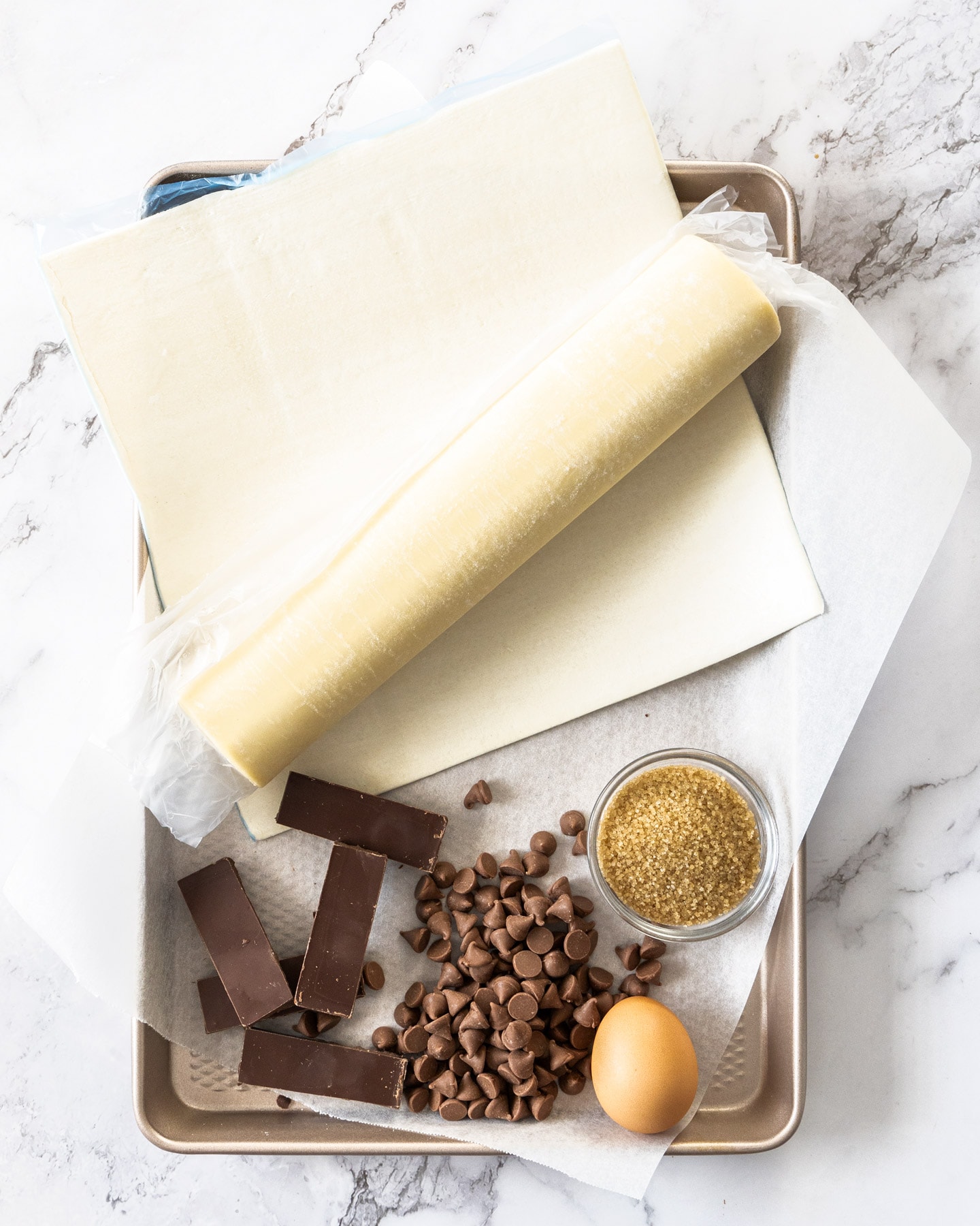 Ingredients for chocolate puff pastries on a baking tray.