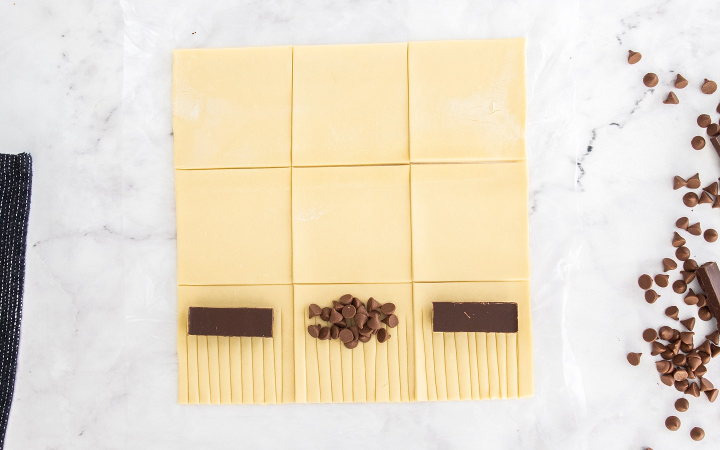 Squares of puff pastry with pieces of chocolate on top.