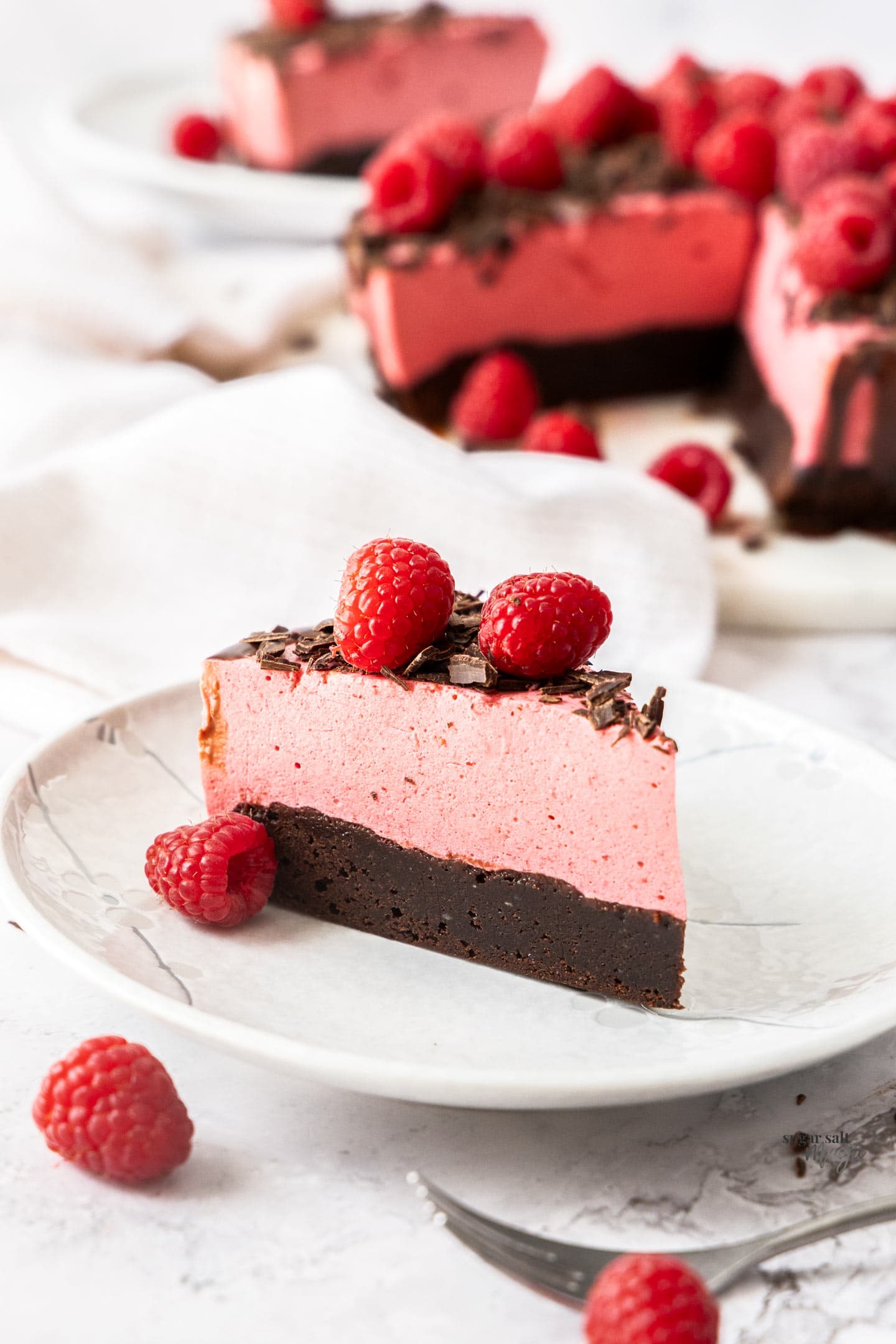 A slice of raspberry mousse cake on a dessert plate.