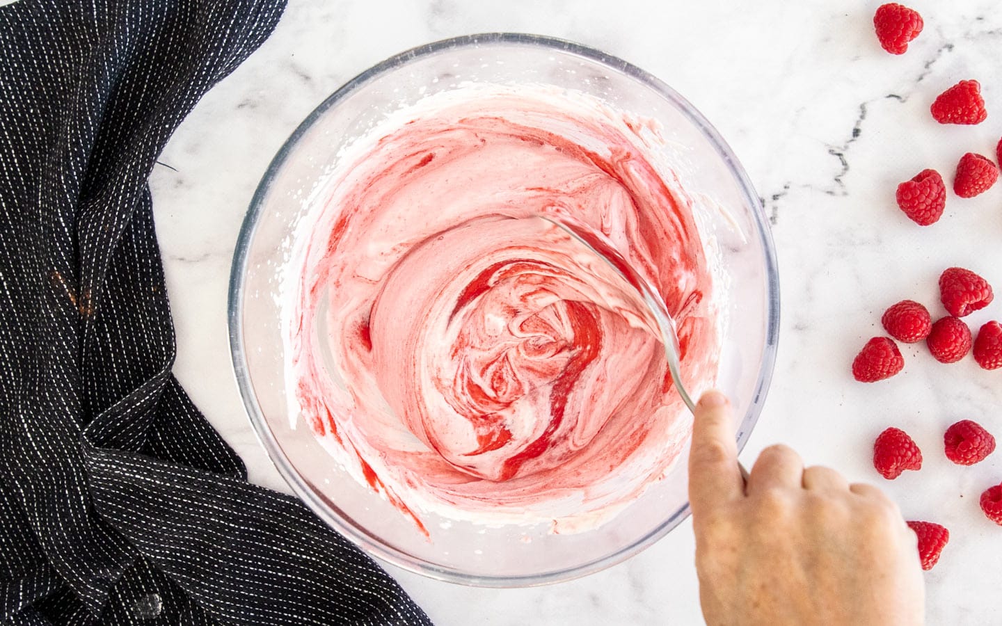 Folding raspberry into whipped cream.