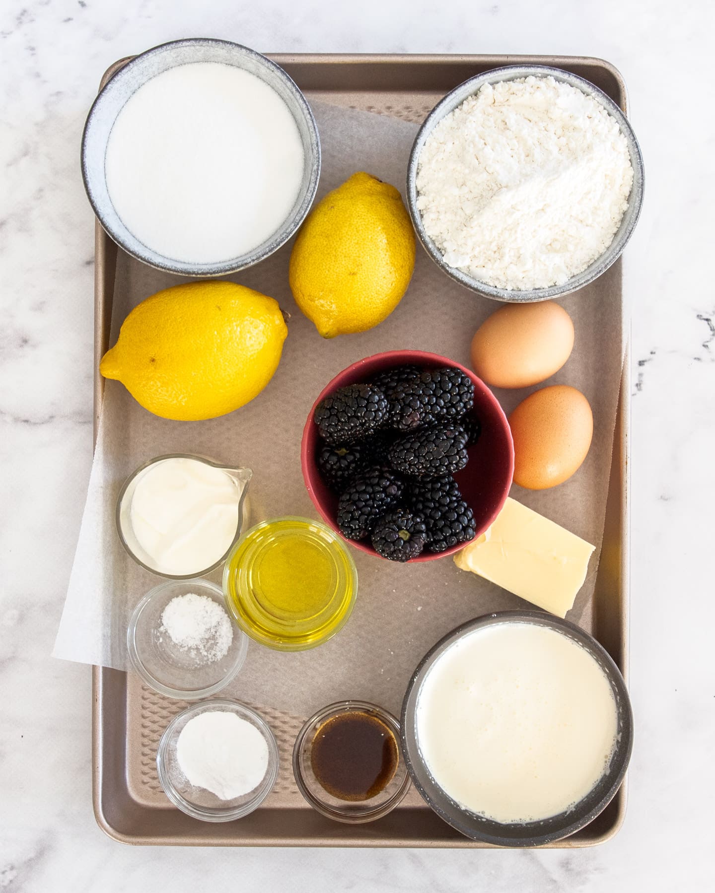 Ingredients for lemon blackberry cake on a baking tray.