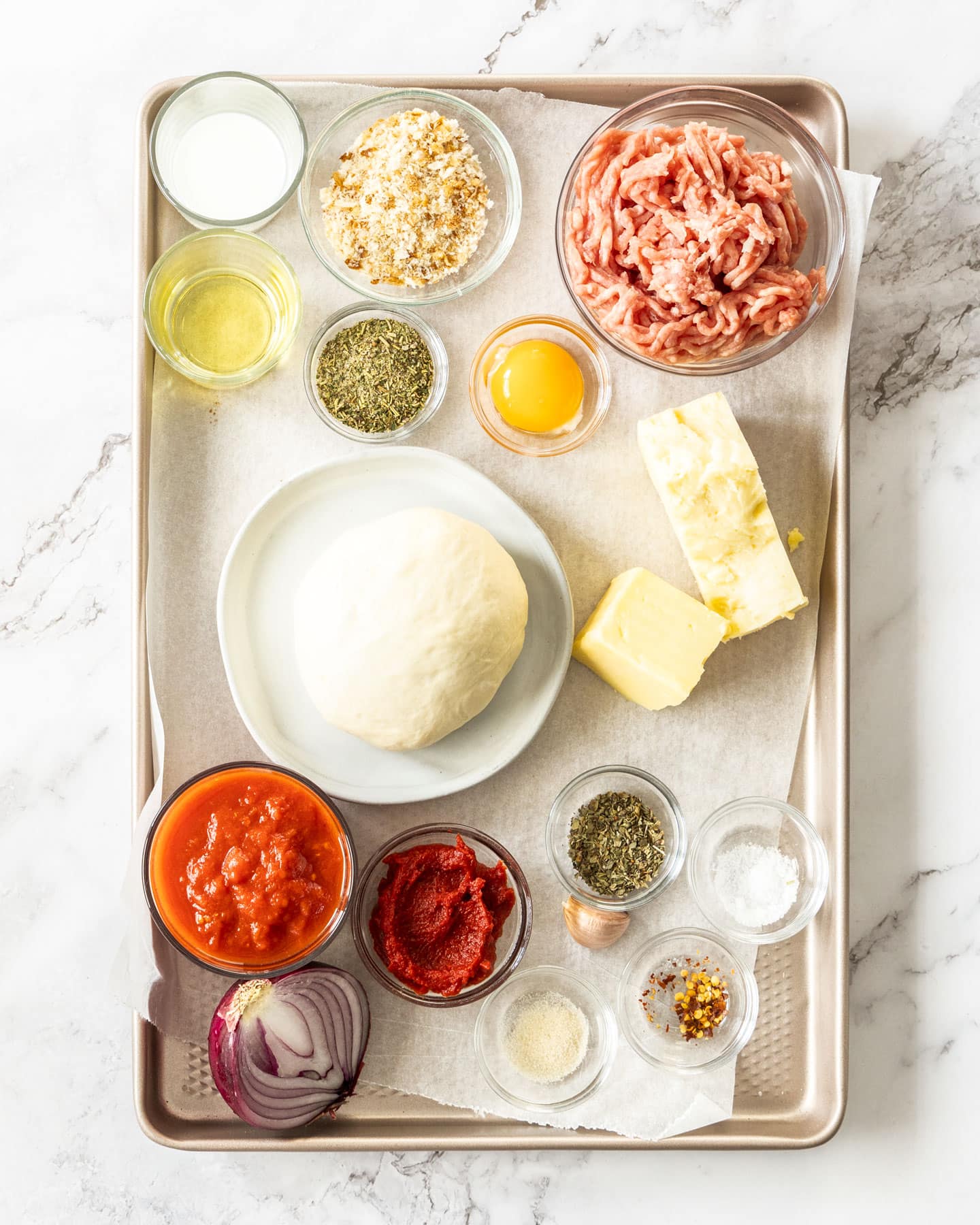 Ingredients for meatball pizza on a baking tray.