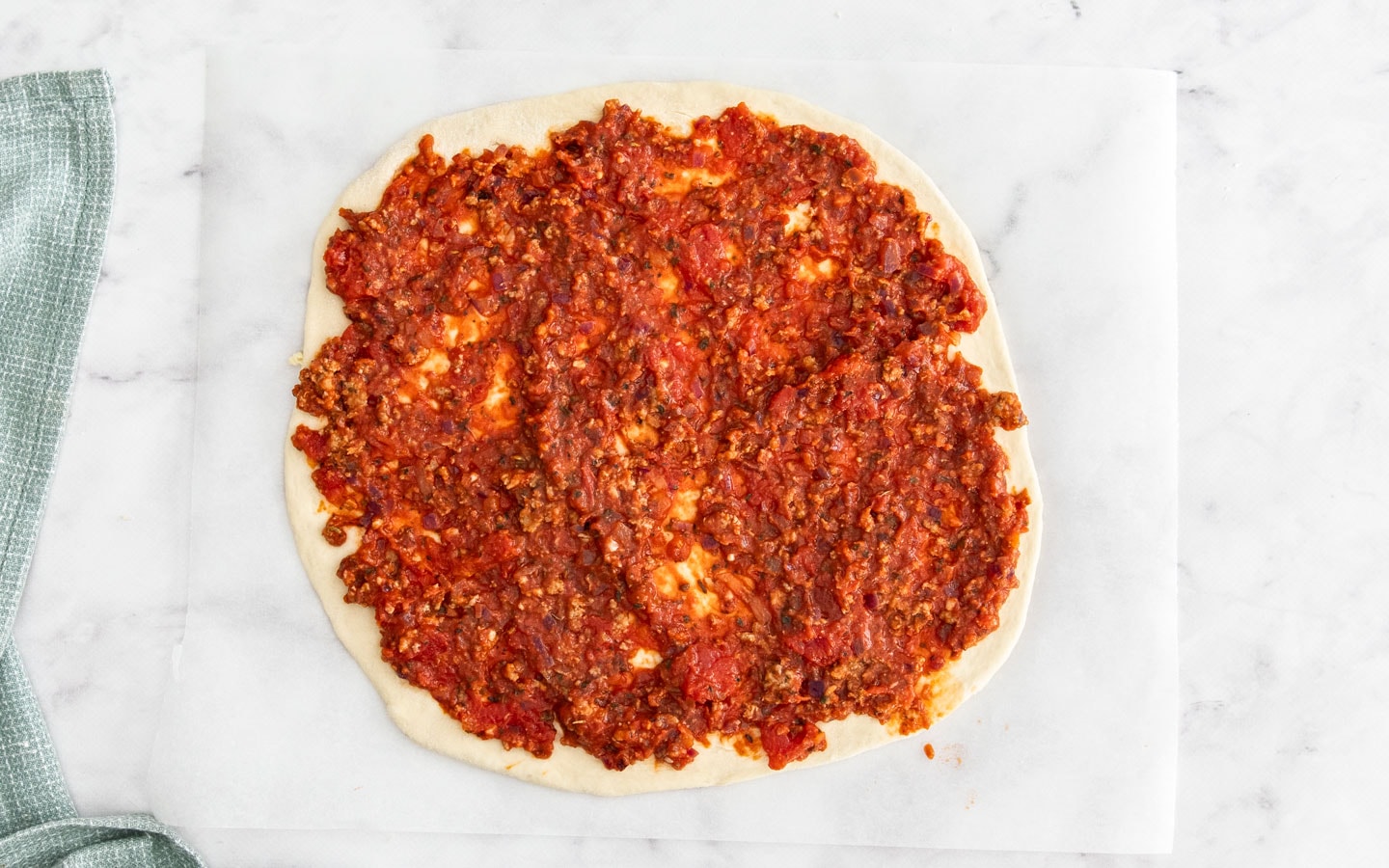 The tomato meat sauce spread on the pizza base.