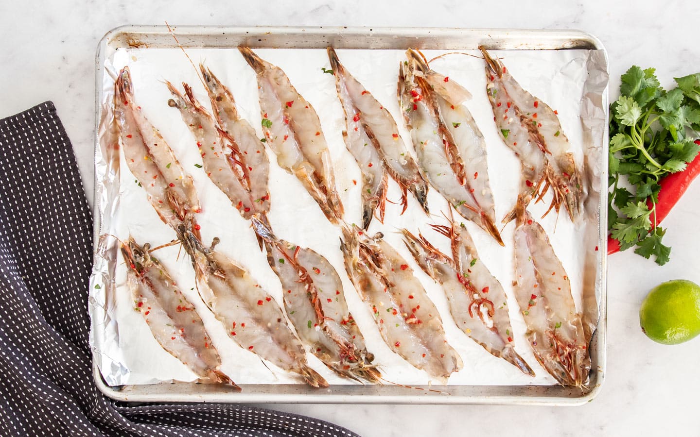12 prawns laid out on a baking sheet ready to cook.