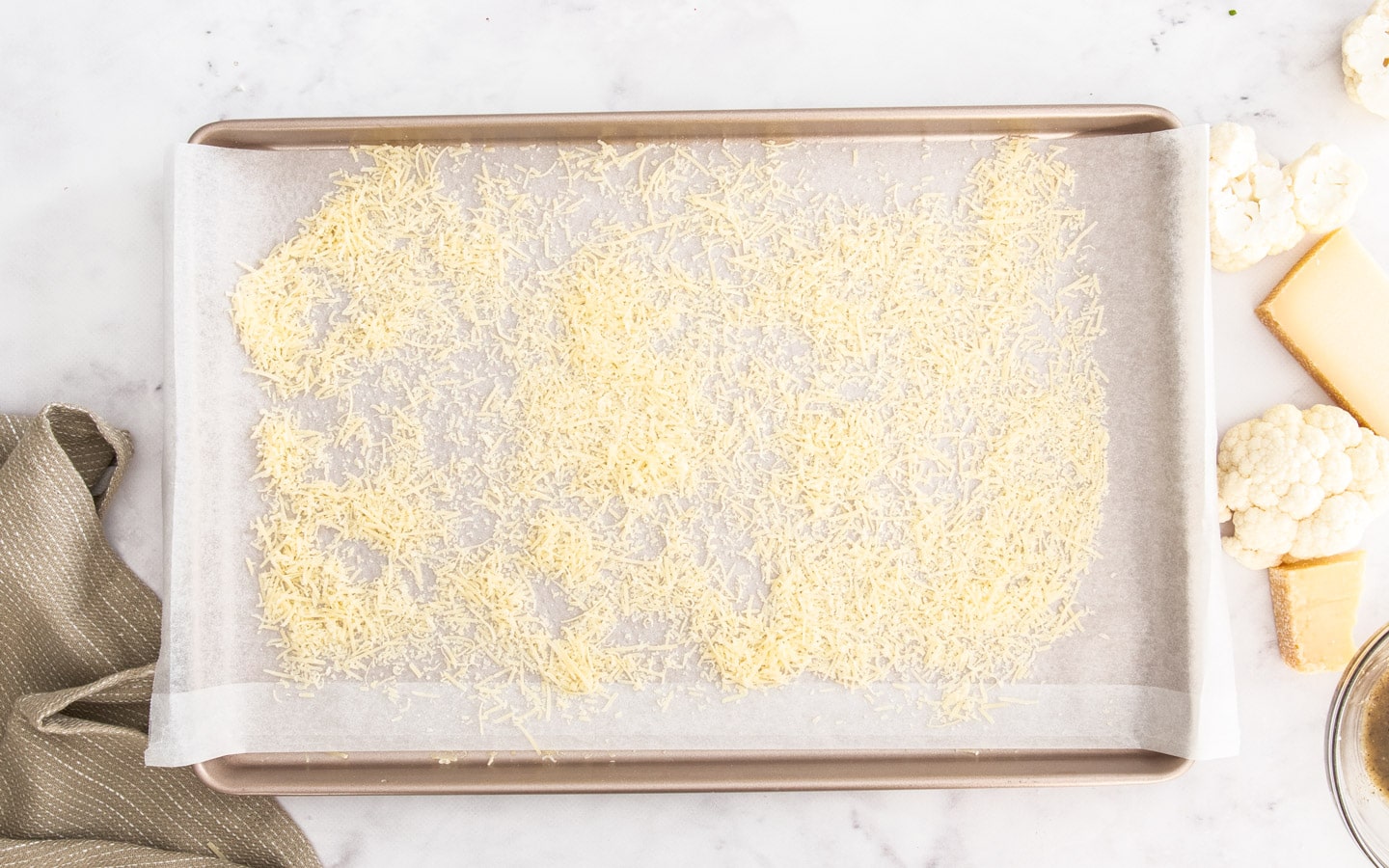 Parmesan cheese scattered over a baking sheet.
