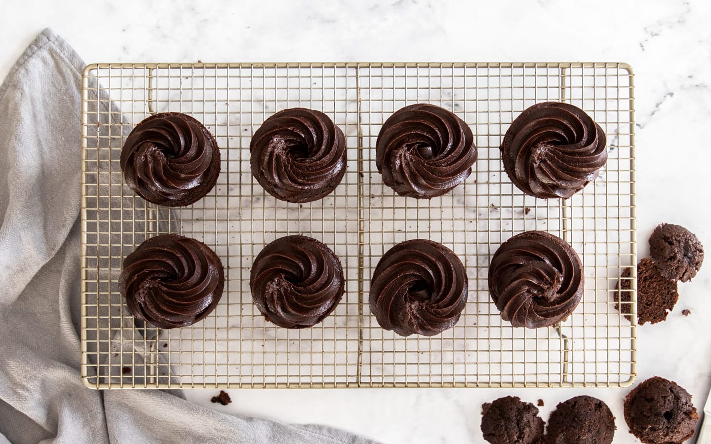 Mini cakes topped with a swirl of chocolate fudge frosting.