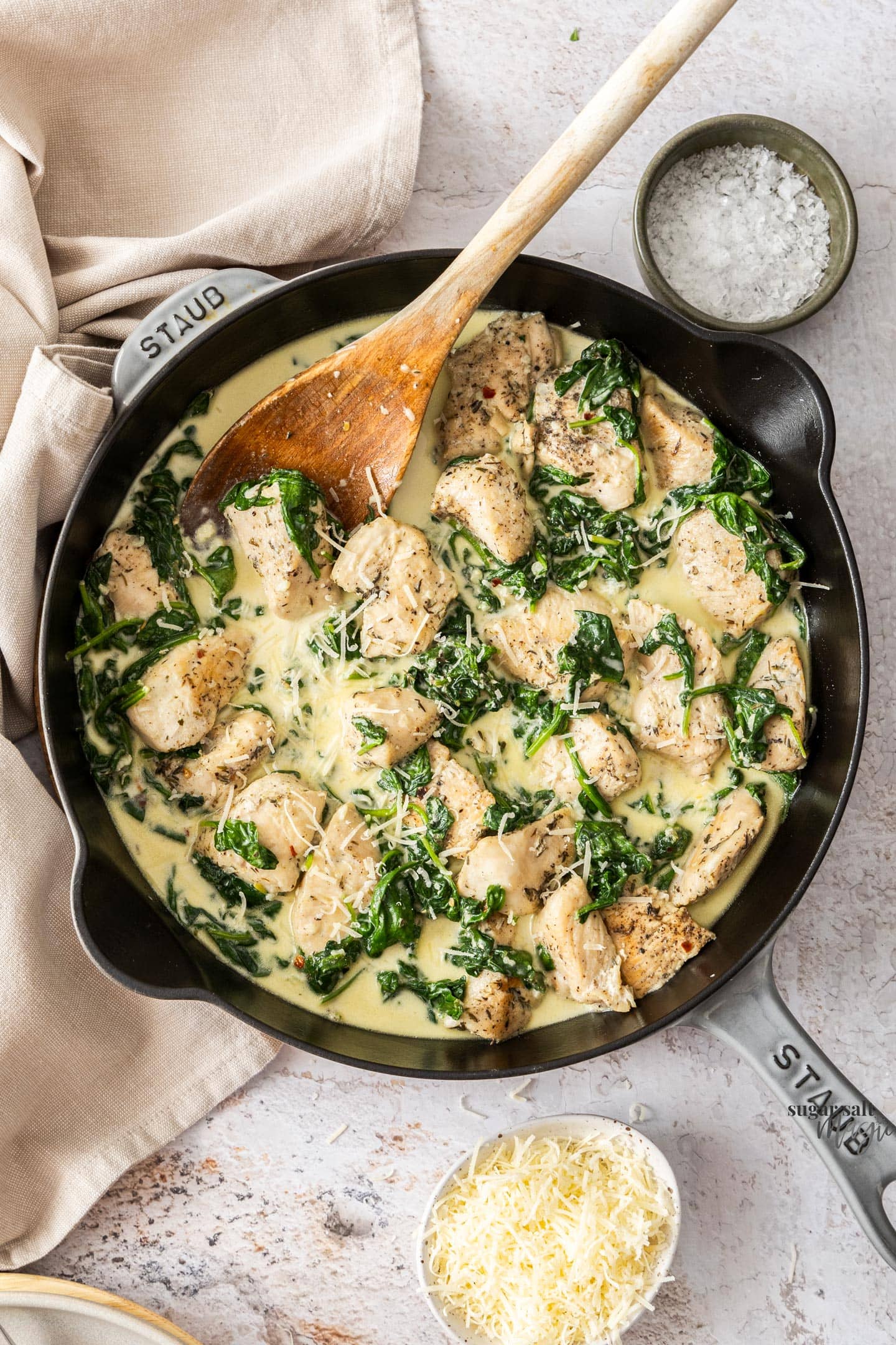 A skillet filled with cooked chicken and spinach in a creamy sauce.