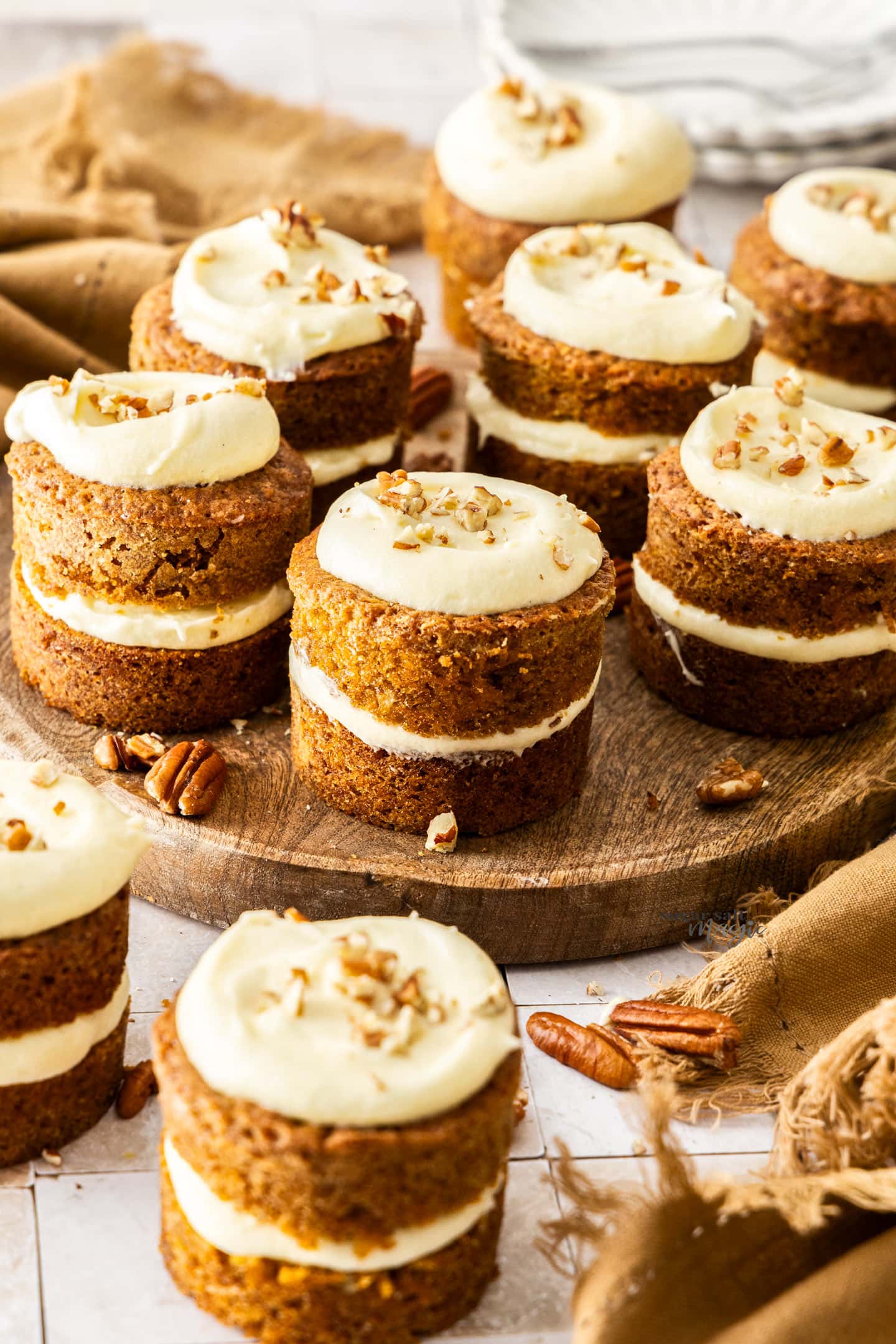 A batch of 9 mini carrot cakes on a wooden platter.