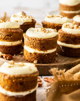 A batch of mini carrot cakes on a wooden platter.