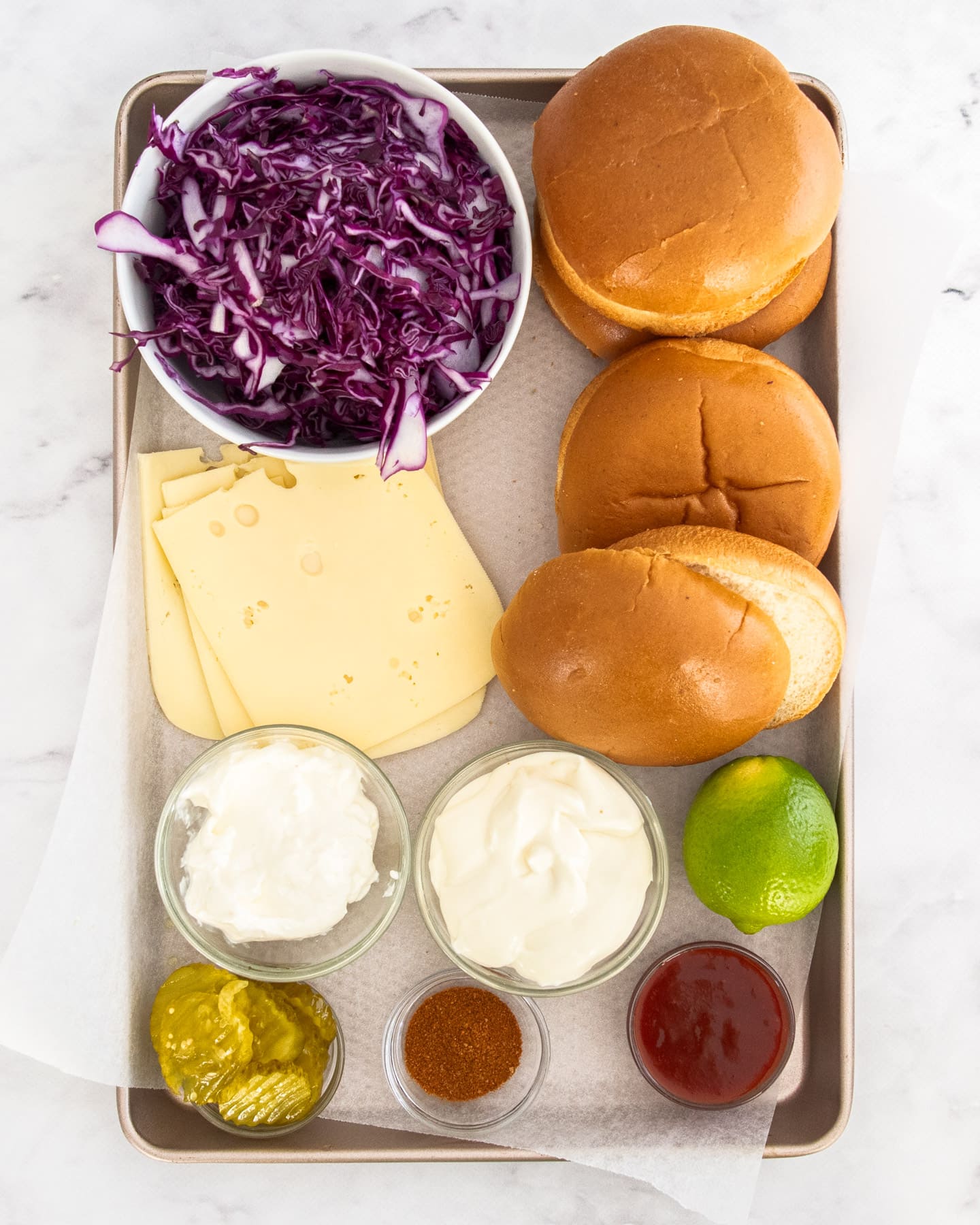 Ingredients for pulled beef burgers on a baking tray.