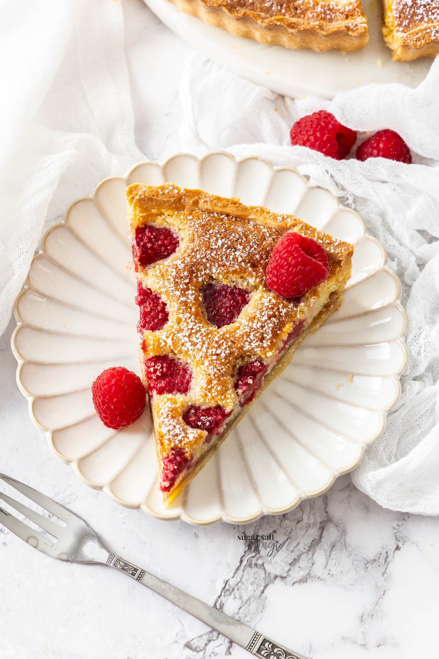 A slice of Raspberry frangipane tart on a dessert plate.
