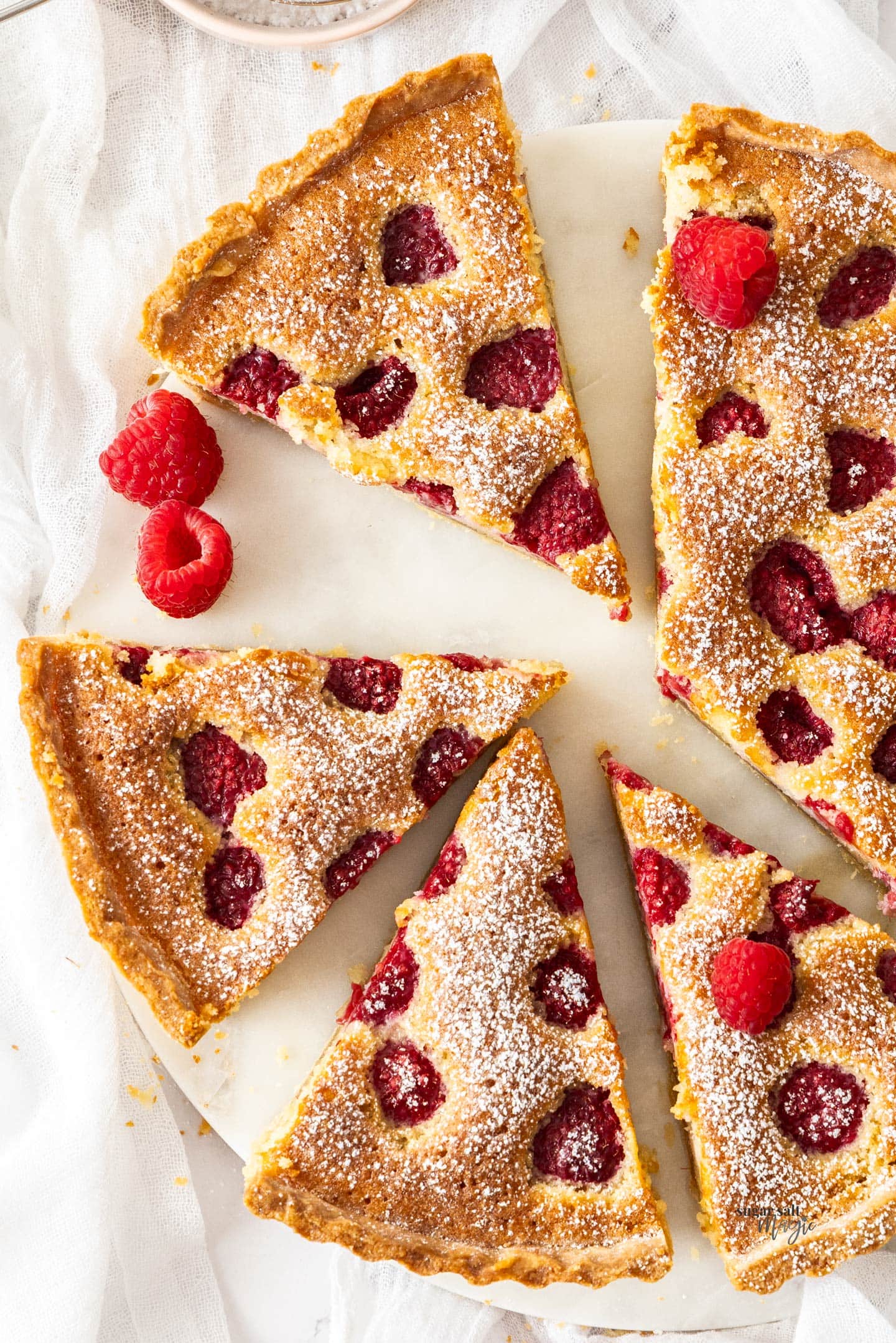 Closeup downwards view of 4 slices of raspberry frangipane tart.