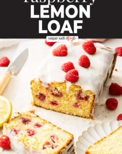 A loaf cake dotted with raspberries with a slice cut away.