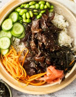 Top down view of the teriyaki beef bowl with cucumber, carrot and edamame beans on the side.