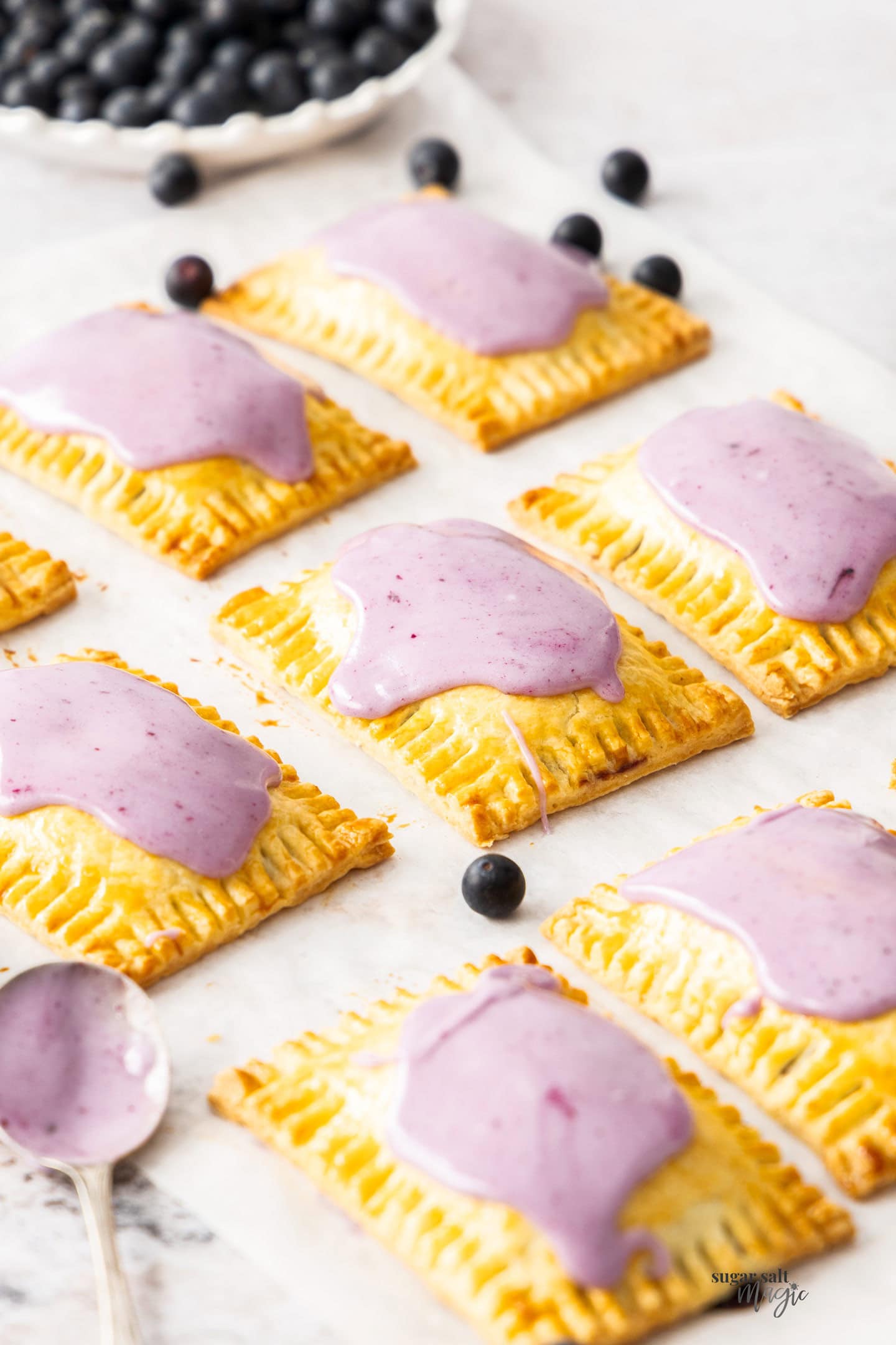 A batch of blueberry pop tarts on a sheet of baking paper.