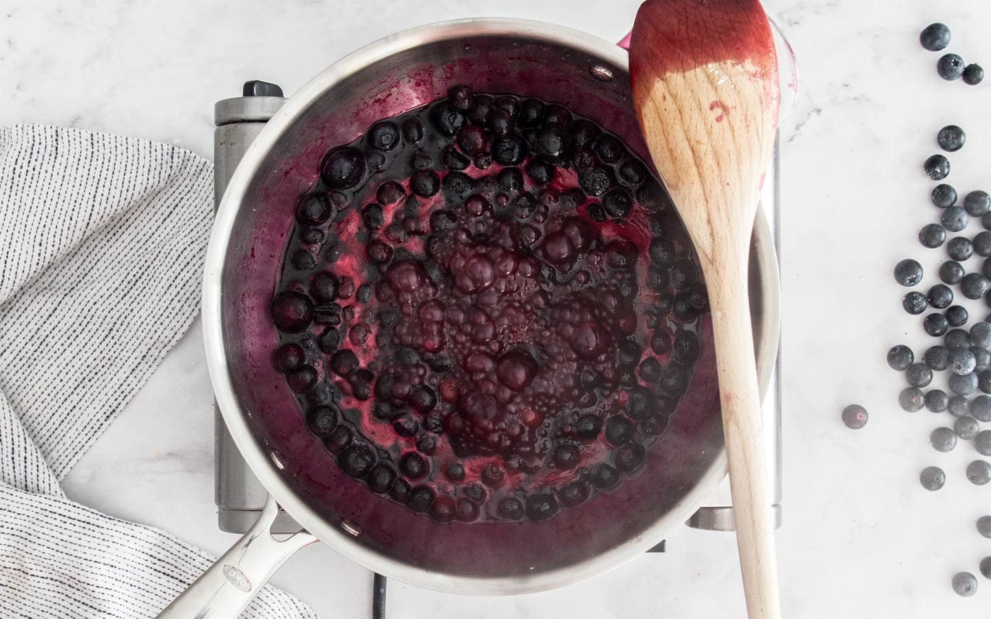 The blueberry sauce boiling in a saucepan.