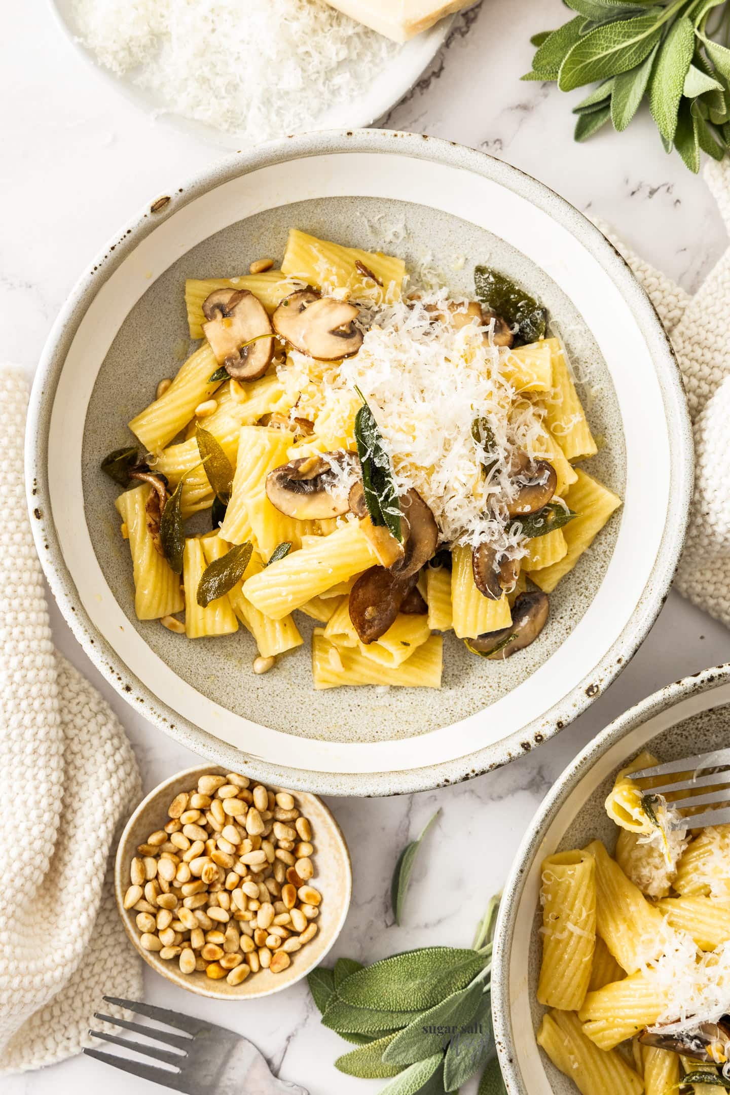 Two bowls of butter sage pasta with a small pinch bowl of pine nuts.