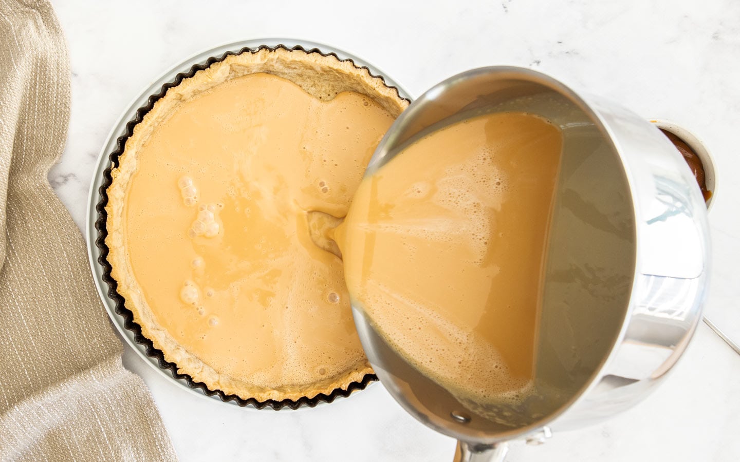 Pouring the caramel custard into the tart shell.