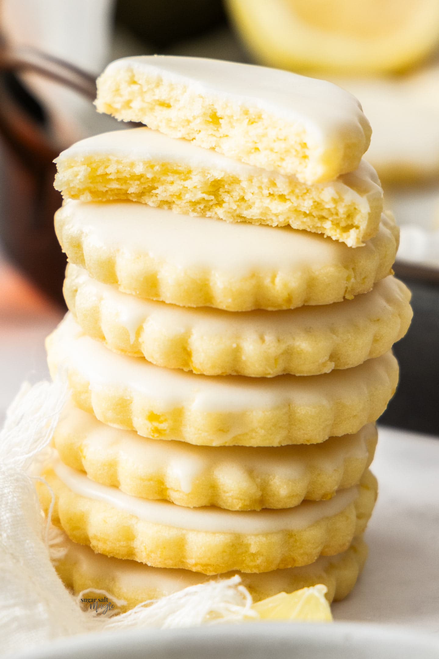 A stack of 7 lemon cookies with the top one broken in half.