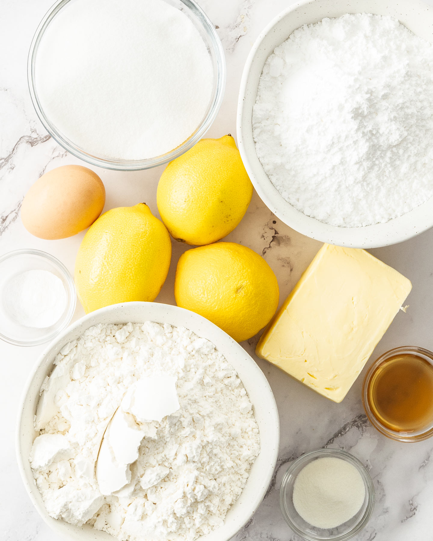 Ingredients for lemon biscuits on a marble surface.