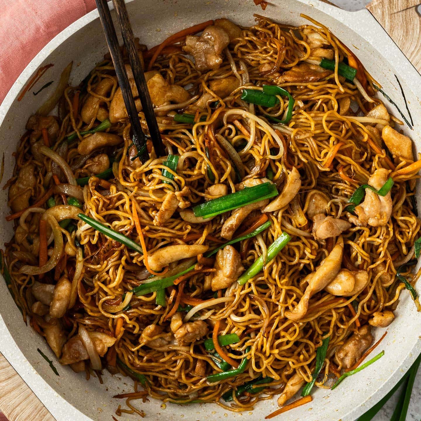 Top down view of chicken chow mein in a pan.