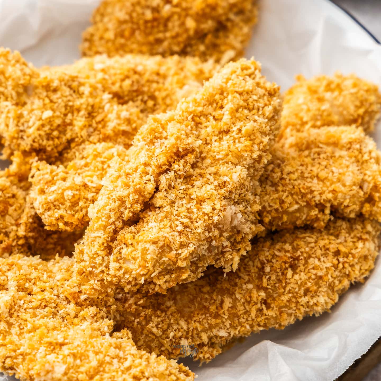 A pile of crunchy chicken tenders in a plate.