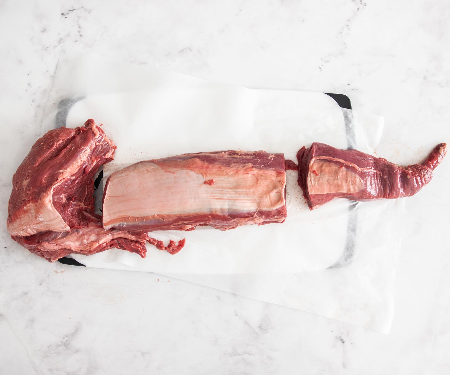 Bacon-wrapped Beef Tenderloin A whole beef fillet cut into 3 pieces with the beef tenderloin in the centre.