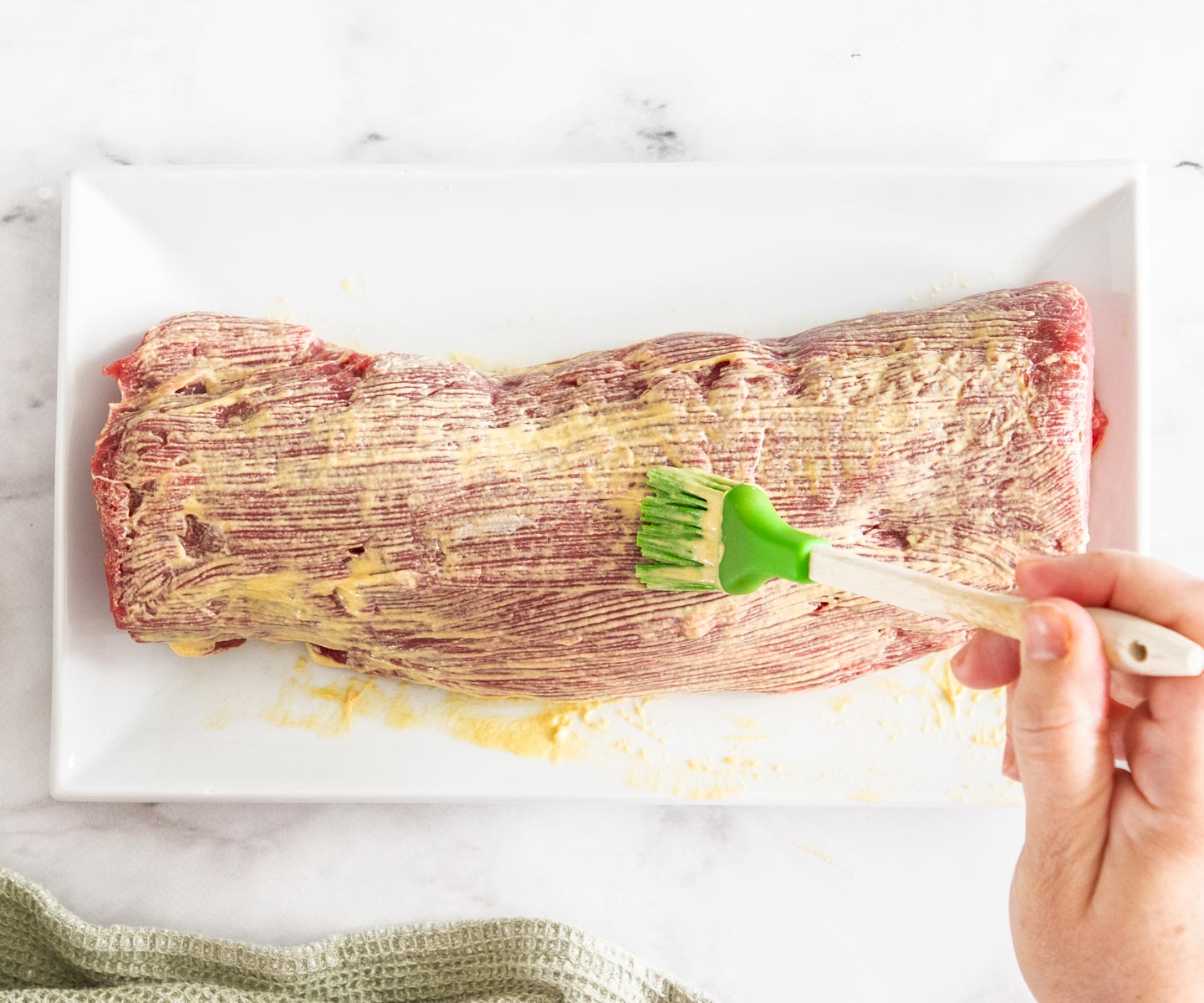 Bacon-wrapped Beef Tenderloin Brushing a beef tenderloin with mustard.