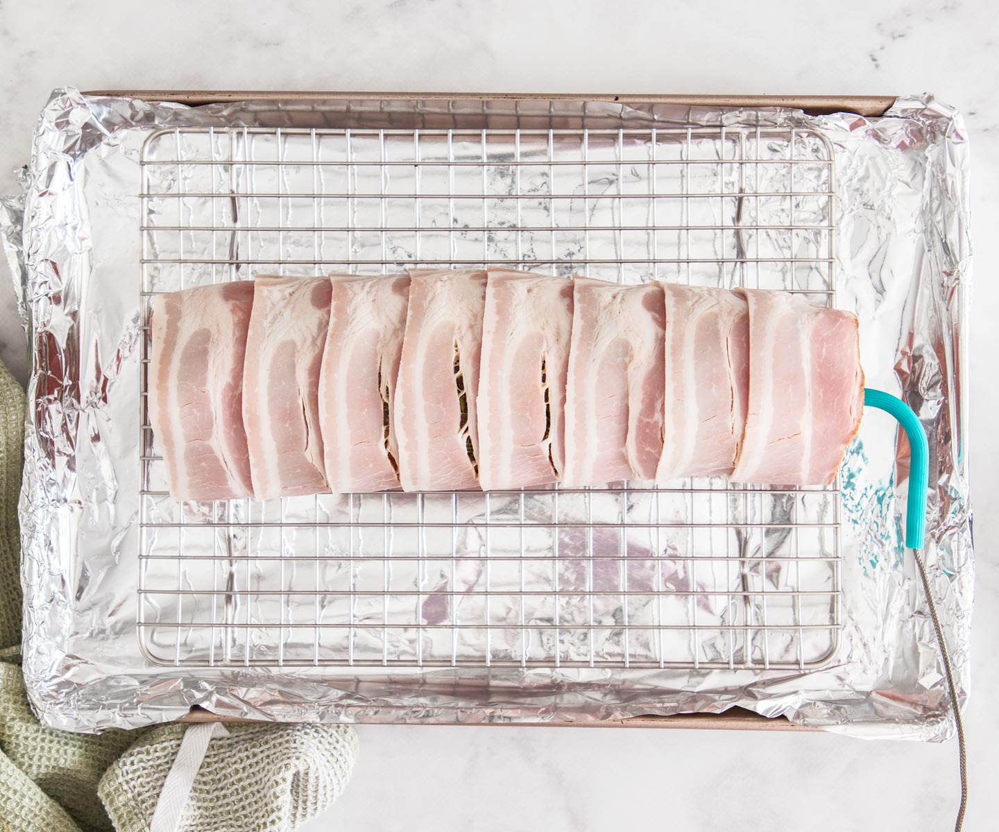 Bacon-wrapped Beef Tenderloin Bacon-wrapped beef tenderloin on a baking tray, ready to roast.