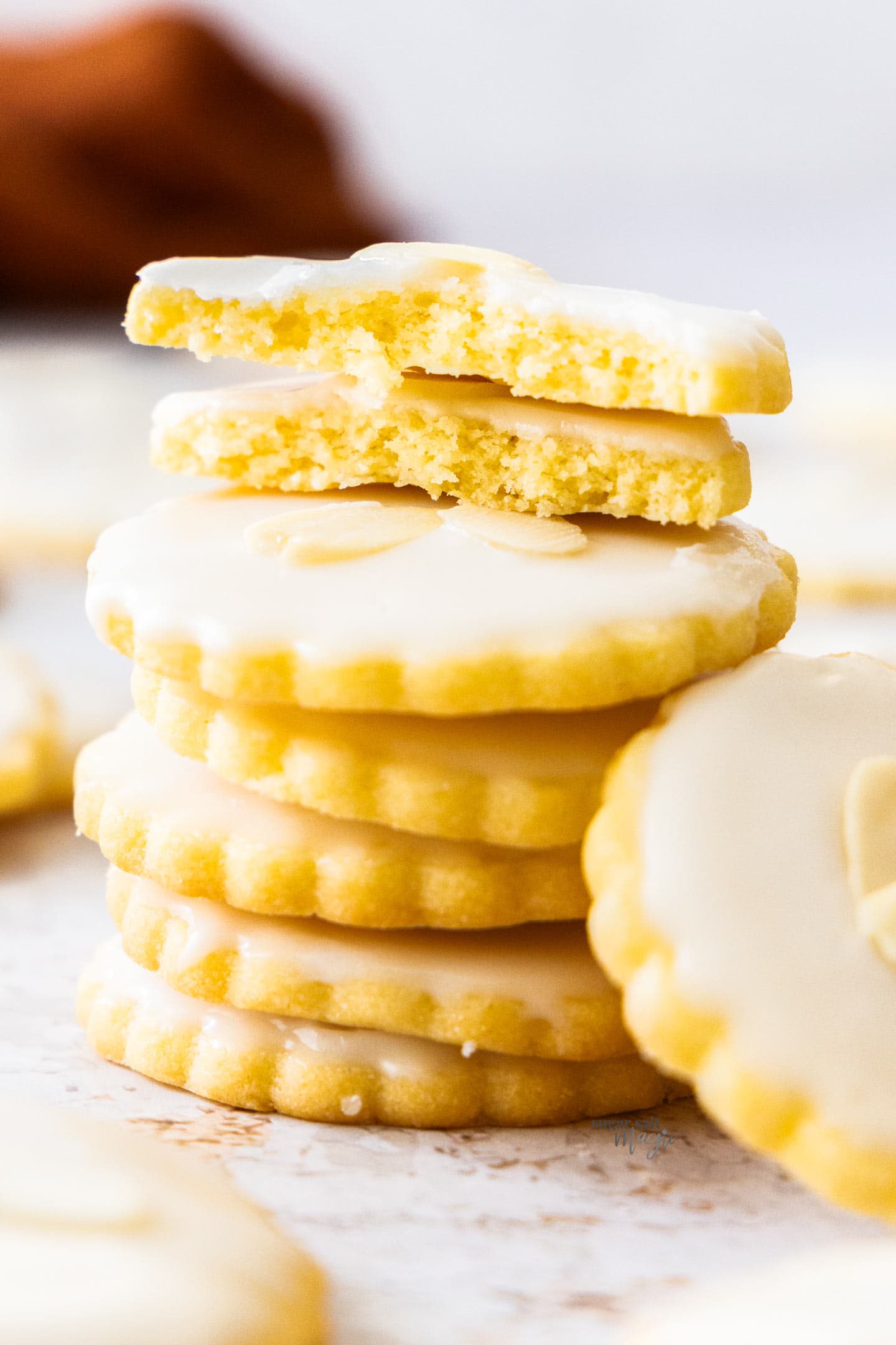 A pile of almond cookies with the top one broken in half to show the texture inside.