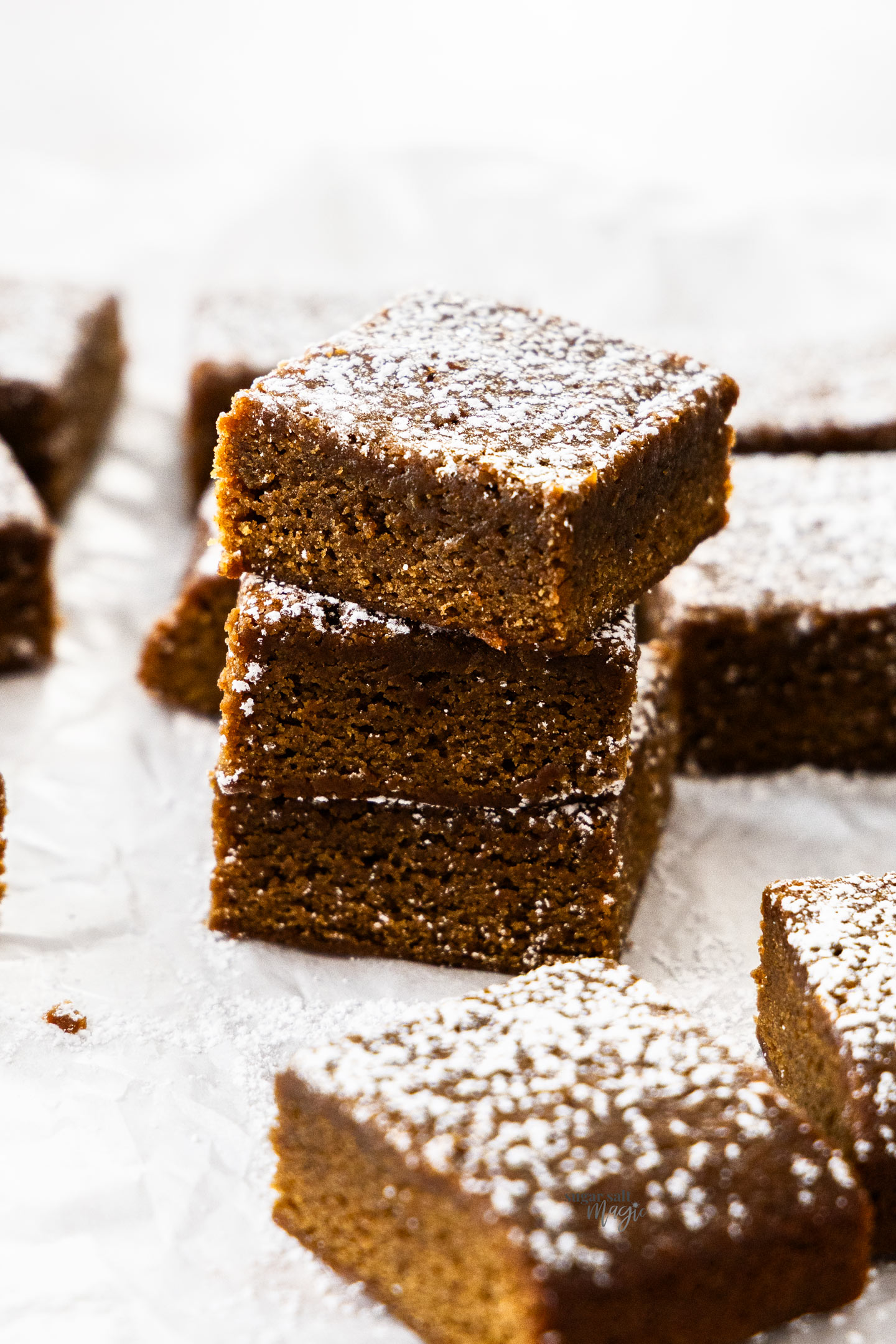 A stack of 3 gingerbread blondies with more surrounding them.