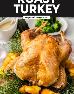 A whole roasted turkey on a wooden board with rosemary and potatoes.