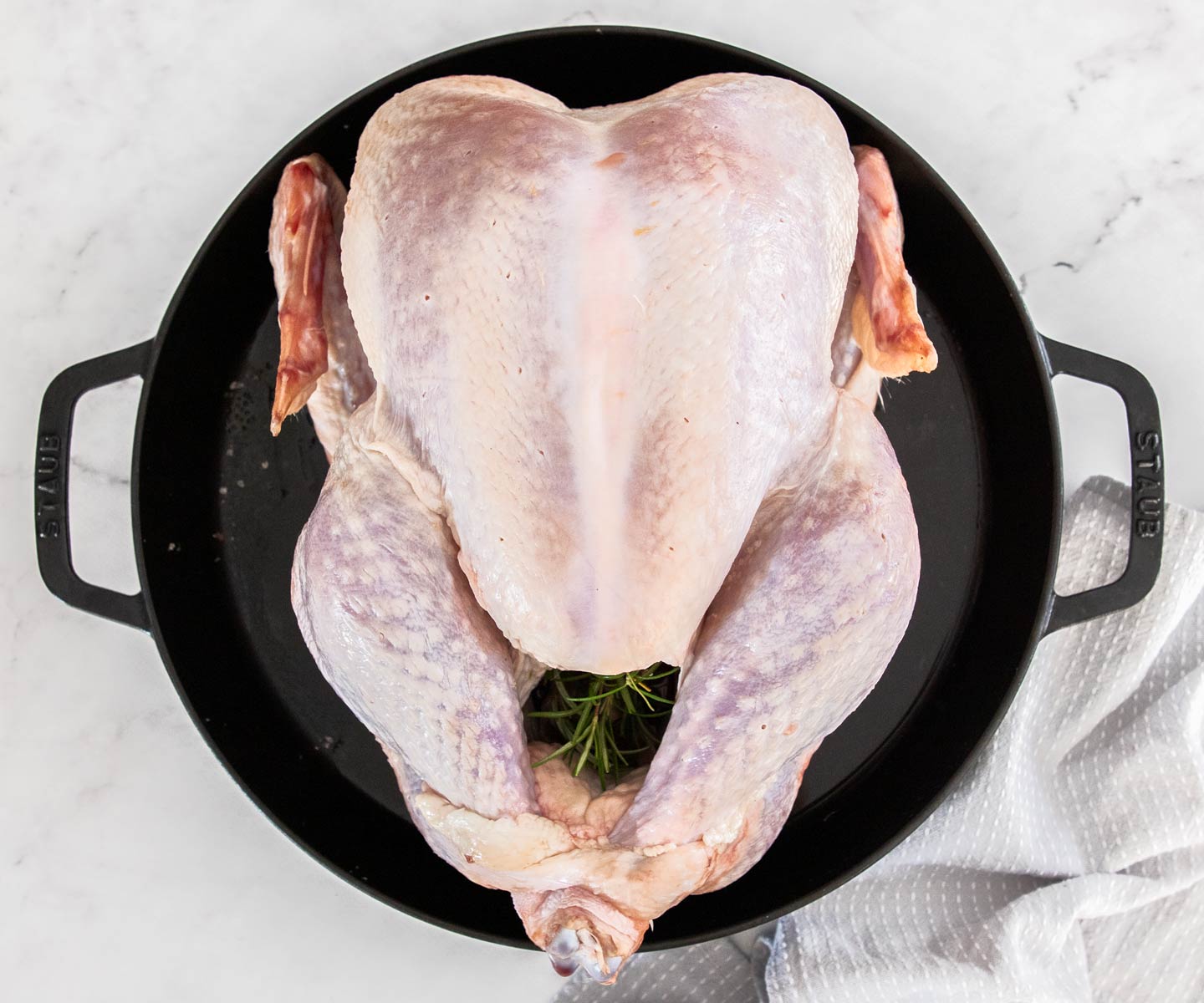 A whole turkey in a large cast iron pan.