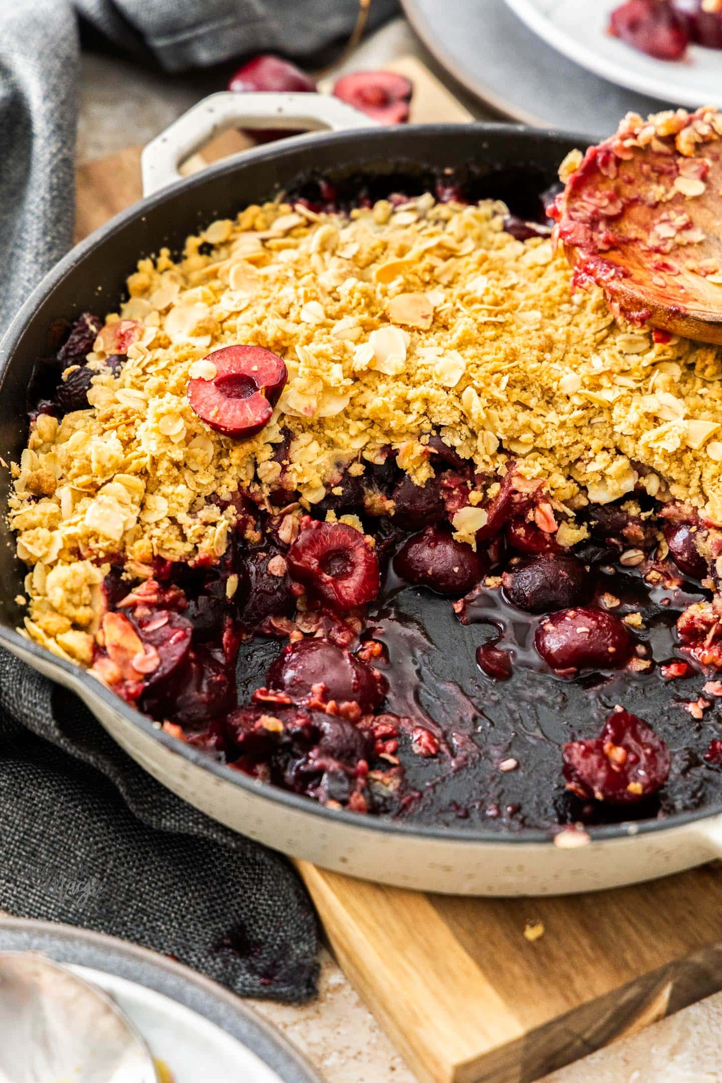 Cherry Crumble Baked cherry crumble in a skillet on a wooden board.