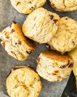 Top down view of 7 date scones in a metal tray with a butter knife next to them.